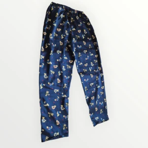 Supergulliga pyjamasbyxor med nallemönster - Mysiga blå pyjamasbyxor med ett gulligt mönster av nallar och röda hjärtan. Perfekta för en avslappnad kväll hemma. Byxorna har en elastisk midja för extra komfort. Byxorna är väl använda och något slitna, se foto från slutet på byxbenen samt någon tråd som gått på framsidan.