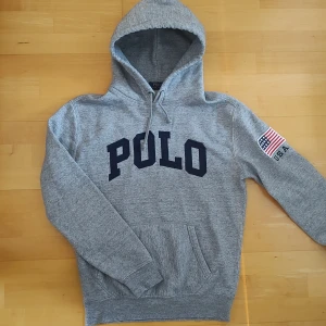 Grå hoodie från Polo Ralph Lauren - Säljer en riktigt snygg hoodie från Ralph Lauren. Stl S, något smal modell men annars true to size. Superskick inga skavanker. Mått från armhåla till armhåla 52cm, bredd längst ner 42cm, längd från mitt på axeln 64cm.