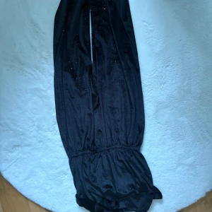 Svarta glittriga byxor med resår - Snygga svarta byxdress med glittriga detaljer och resår i midjan samt vid benslut. Byxdressen har en loose passform och är perfekta för dig som vill sticka ut lite extra. Materialet känns mjukt och följsamt.
