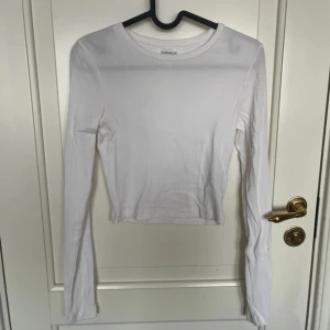 Vit ribbad långärmad topp Even&Odd - En basic vit långärmad topp från Even&Odd i ribbad bomull. Modellen är croppad med rund halsringning och sitter snyggt figurnära. Perfekt att styla med jeans eller kjol för en clean look.