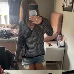 Svartvit omlottkofta från Holebrook - Snygg svartvit omlottkofta från Holebrook med knytband i sidan. Koftan har ett tätt stickat mönster och svarta kanter. Perfekt för dig som gillar klassisk stil med en twist. Långärmad och i mjuk bomullskvalitet.Går själv klart att diskutera priset🩷🩷