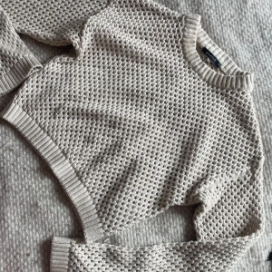 Beige stickad tröja från Bik Bok - Säljer en beige stickad tröja från Bik Bok . Tröjan har ett grovt hålmönster, rund halsringning och ribbade muddar vid ärmslut och nederkant. 