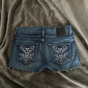 Vintage jeans shorts - Mörkblå lågmidjade vintage jeansshorts från G-star med snygg pärldesign på fickorna. Midjemått 34cm. I jättebra skick❤️