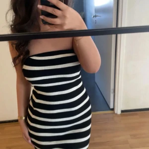Randig tubklänning i svart och vitt - Säljer en tight, ribbad tubklänning med svarta och vita horisontella ränder. Klänningen är kort och ärmlös, sitter figurnära och har en enkel, stilren look. Perfekt för dig som gillar en clean och trendig stil. Slutsåld 