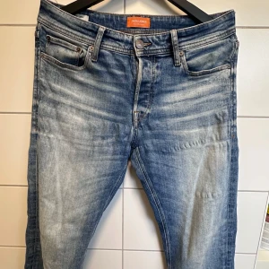 Blå jeans från Jack & Jones, stl 31/32 - Snygga blå jeans från Jack & Jones i klassisk femficksmodell. Jeansen har en tvättad look med ljusa partier och raka ben. Perfekta för dig som gillar en avslappnad stil med lite slitningseffekt. Midjehöjd och passform är normal.