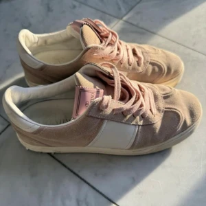 Valentino Rockrunner sneakers rosa/vit - Snygga Valentino Rockrunner sneakers i ljusrosa mocka och vitt skinn. Skorna har rosa snörning, vit panel på sidan och rosa detaljer på plösen. Klassisk rund tå och platt sula med små nitar baktill. Tyvärr är en nit borta men annars är det strålande skick på dem