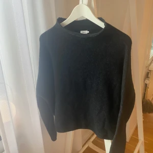 Svart stickad tröja Filippa K storlek M - Mika Yak Funnelneck från Filippa K. Mysig svart stickad tröja med enkel och stilren design. Tröjan har lite högre hals och en något lös passform. Som ny, ej använd endast provad. Nypris 3200:-