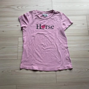 Rosa t-shirt från CRW med tryck - Rosa t-shirt från CRW med texten 'I love my Horse' och ett hjärta på bröstet. Klassisk rund halsringning och korta ärmar. Skön och mjuk i bomull, perfekt för dig som gillar hästar och vill ha en chill stil. Är i storlek 158/164 men känns som storlek 140.