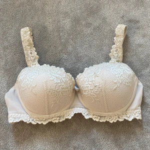 Beige spets-bh med rosett - Beige intimissimi bh i storlek 75C, jättebra skick bar att rosetten i mitten är sönder men inget som märks när man har den på sig!💗