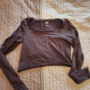 Svart croppad långärmad topp 157 - Svart croppad långärmad topp från 157 med rundad, lite bredare halsringning. Tillverkad i mjuk bomullsmix med lite stretch för en skön passform. Perfekt att matcha med höga jeans eller kjol för en chill look. Kort modell 