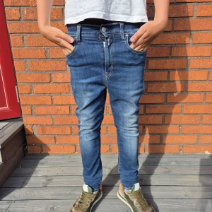 Blå replay jeans slim fit - Blp replay jeans slim fit. Jeansen har klassiska fem fickor, dragkedja och knapp i midjan samt snygga slitningar framtill. Perfekta för en avslappnad och trendig look. Priset ej hugget I sten