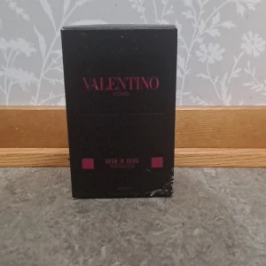 Valentino Uomo Born In Roma EdP - Säljer en Valentino Uomo Born In Roma EdP. Flaskan är svart med nitar och har en lyxig, edgy design. Märkets logga syns i rosa på både flaskan och kartongen. Perfekt för dig som gillar exklusiva och moderna dofter.