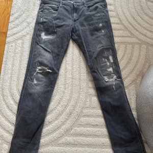 Mörkgrå slitna skinny jeans - Säljer ett par mörkgrå replay anbass med slitningar och trasiga detaljer på benen. Strl W33 L34