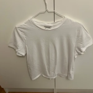 Vit basic t-shirt från Monki - Enkel och stilren vit t-shirt från Monki i storlek S. T-shirten har rund halsringning och korta ärmar, perfekt för en clean och avslappnad look. Tillverkad i mjuk bomull som känns skön mot huden.