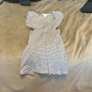 Randig kortklänning från Zara - Superfin kortklänning från Zara med svartvita ränder. Klänningen har resår i midjan och är gjord i mjuk bomull, perfekt för en chill och snygg look. Enkel att styla med sneakers eller sandaler.