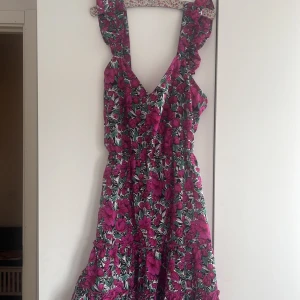 Blommig klänning från Shein - Säljer en färgglad blommig klänning från Shein med rosa och gröna blommor. Klänningen har volangdetaljer och är öppen i ryggen med knytning💕