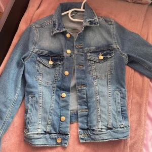 Blå jeansjacka från BDENIM - Säljer en klassisk blå jeansjacka från BDENIM i storlek S. Jackan har knappar framtill och två bröstfickor med knappstängning. Perfekt för vår och sommar!
