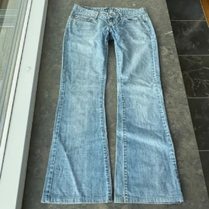 Blå bootcut jeans från Only - Snygga ljusblå bootcut jeans från Only med klassisk femficksdesign och knappgylf. Perfekta för en avslappnad stil med en touch av retro. Passar bra till sneakers eller boots. Innerbenslängden är 76 cm och midjemåttet är 39 cm❤️