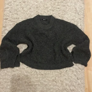 Mörkgrå stickad tröja från Gina Tricot - Säljer en mysig mörkgrå stickad tröja från Gina Tricot. Tröjan har en ribbad struktur och långa ärmar med ribbade muddar. Slits vid ärmarna och på sidorna. Perfekt för kyliga dagar. Hör av dig vid intresse!