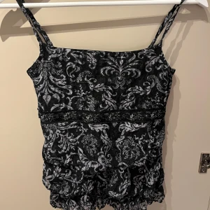 Svart och vit mönstrad linnetopp från KappAhl - Säljer en snygg svart och vit mönstrad linnetopp från KappAhl. Toppen har smala axelband och ett elegant mönster som ger en stilren look. Perfekt för att piffa upp garderoben!