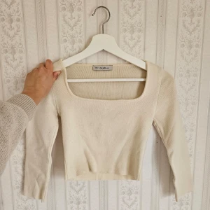 Topp med trekvartsärm  - Säljer en stilren krämvit ribbad topp från Chiquelle. Den har en fyrkantig urringning och trekvartsärmar, vilket ger en elegant look. Perfekt för att matcha med både jeans och kjol. Passar bra till både vardag och fest.🩷