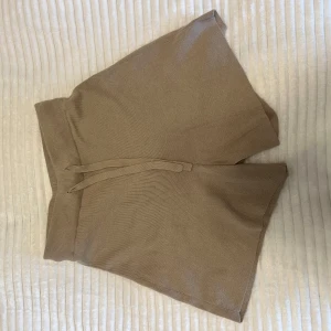 Beige shorts i kashmirblandning från H&M - Säljer ett par mjuka och bekväma beige shorts från H&M i en lyxig kashmirblandning. De har en ribbad midja och knytband för justerbar passform. Perfekta för en avslappnad stil.⭐️