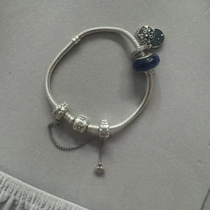 Pandora armband - Elegant silverarmband med flera berlocker från Pandora❤️En blå glittrig pärla, en med stjärndetaljer och en säkerhetskedja❤️hela armbandet kommer med❤️ Superfin och använd fåtal gånger❤️köptes för ca 3000 kr totalt❤️ säljer för ca 1000 kr❤️