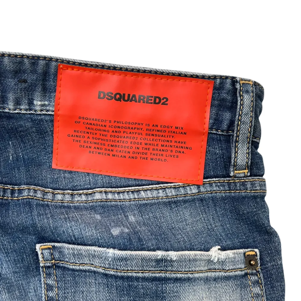 Säljer ett par coola blå jeans från DSQUARED2 med slitna detaljer och en vintage look. Jeansen har en klassisk femficksdesign och en röd logolapp bak. Perfekta för en avslappnad stil.. Farkut & Housut.