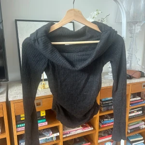 Svart off shoulder topp - Säljer en stilren  ribbad off shoulder topp med croppad längd och långa ärmar. Materialet är en blandning av viskos, polyester och polyamid vilket ger en mjuk och stretchig känsla. Passar perfekt till både jeans och kjol!