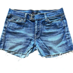 Blå jeansshorts med fransar - Supersnygga lowwaist jeansshorts med dubbla knappar perfekta för sommaren! Några små slitningar i grenen men de är bara att skriva om bild behövs!💕.                                                   Midja mätt platt: 37,5 cm                                            Grenen: 21,5 cm                                                            Priset går alltid att diskuteras. Skriv om de finns några frågor💕
