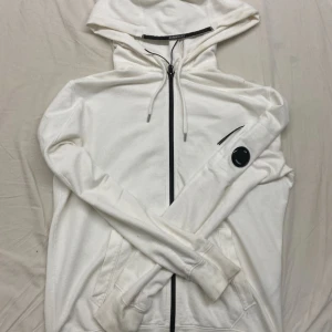 C.P. Company Vit Zip Hoodie - Säljer en vit C.P. Company zip-hoodie i Diagonal Raised Fleece. Bra skick!, obs en gul fläck på ärmen pm för bild. 