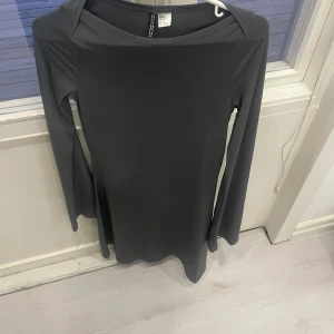 Grå klänning från H&M Divided - Säljer en stilren grå klänning från H&M Divided. Klänningen har en enkel design med långa ärmar och en rak passform. Perfekt för en minimalistisk look.
