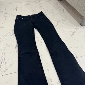 Svarta jeans med bootcut - Snygga svarta jeans med bootcut och låg midja. De har klassiska fem fickor och en dragkedja med knapp framtill. Perfekta för en avslappnad stil.