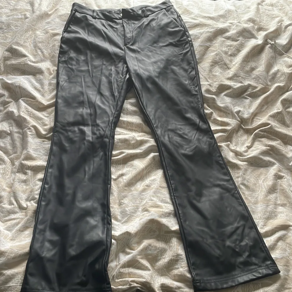 Snygga svarta skinnbyxor från ONLY med bootcut-stil. Perfekta för en trendig look. Byxorna har en medel midja och en stilren design som passar till många olika outfits.. Farkut & Housut.