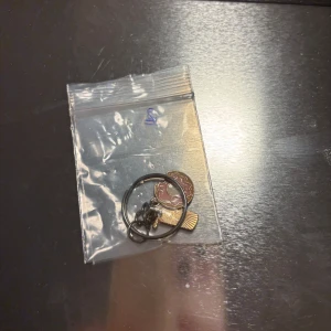 Nyckelring med berlocker - Säljer en nyckelring med flera berlocker, inklusive en rosa blomma och en kam. Perfekt som accessoar för att ge din nyckelknippa lite extra stil.