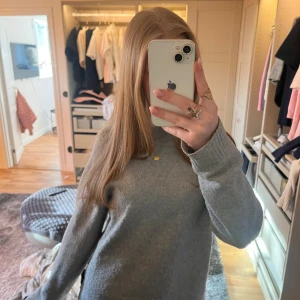 Grå stickad tröja - Säljer en mysig grå stickad tröja med rund hals och långa ärmar. Perfekt för kyligare dagar och lätt att matcha med olika outfits. Tröjan har en enkel och stilren design.