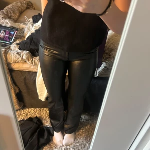 Svarta skinnbyxor - Snygga svarta skinnbyxor med tight passform. Perfekta för en stilren look och kan enkelt matchas med olika toppar. Byxorna har en glansig finish som ger en extra touch av elegans.