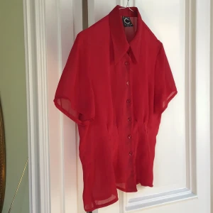 Röd kortärmad blus från C Clothes - Snygg röd blus från C Clothes med korta ärmar och knappar framtill. Perfekt för en färgglad look. Storlek 40.