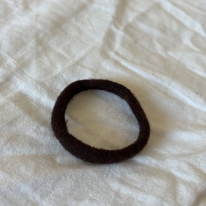Brun hårsnodd - En enkel brun hårsnodd perfekt för att hålla håret på plats. Den är elastisk och mjuk, vilket gör den skonsam mot håret. Passar bra för daglig användning.