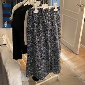 Blommig långkjol i blått och svart - Säljer en långkjol med ett fint blommigt mönster i blått, svart och beige. Den är gjord i ett lätt och luftigt material. Storlek xss-xs, köpt ifrån uniqlo för 500 kronor.