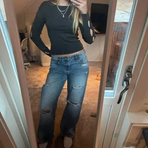 Svart långärmad topp med cutouts - Snygg svart långärmad topp med unika utskärningar längs ärmarna. Färgen är lite urtvättat grå typ. Jätte fin unik tröja!!❤️❤️