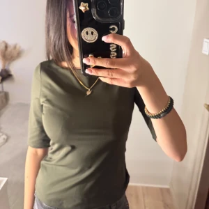 Olivgrön topp med trekvartsärm - Säljer en stilren olivgrön topp med trekvartsärm. 