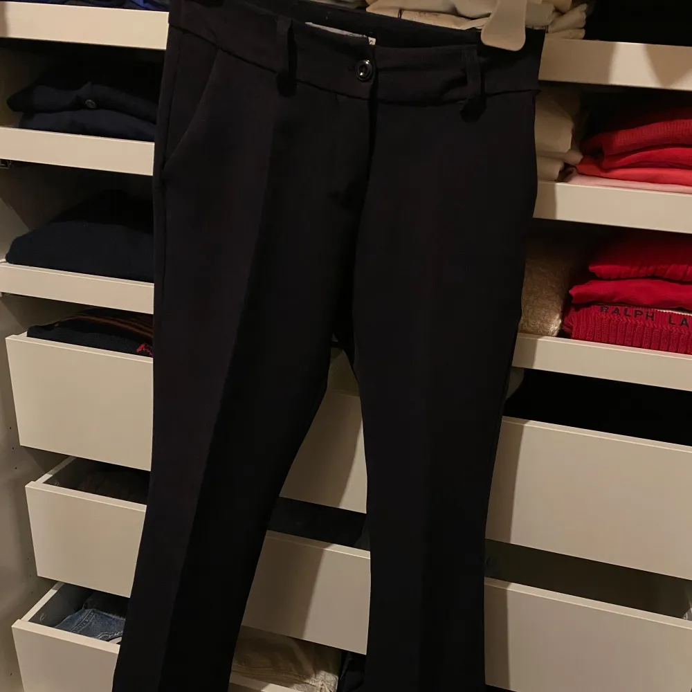 Snygga svarta kostymbyxor från Design Si i storlek XS. Byxorna har en klassisk design med knappar och hällor för bälte. Perfekta för en stilren look.. Farkut & Housut.