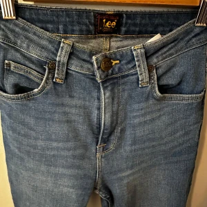 Lee Breese Bootcut jeans blå W25 L31 - Snygga blå bootcut jeans från Lee, modell Breese Boot. Klassisk femficksdesign, normal passform och hög midja. Jeansen är i ett mjukt denimtyg med lätt tvättad look och har dragkedja och knapp framtill.