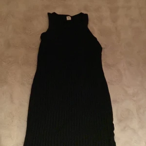 Svart ribbad ärmlös klänning SHEIN - Svart ribbad klänning från SHEIN i ärmlös modell. Klänningen har en enkel, tight passform och rund halsringning. Perfekt för dig som gillar stilrena och minimalistiska plagg. Materialet är stretchigt och bekvämt.