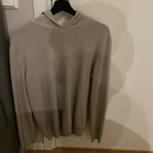Beige hoodie från Oscar Jacobson M - Säljer en stilren beige hoodie från Oscar Jacobson i storlek M. Tröjan har lång ärm, huva och är tillverkad i ett mjukt material som känns lyxigt. Perfekt för dig som gillar en clean och enkel look med premiumkänsla.