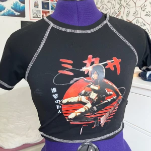 Anime-topp - Svart topp med tryck av Mikass från Attack o. Titan. Tyvärr håller motivet på att gå av längst ner. 