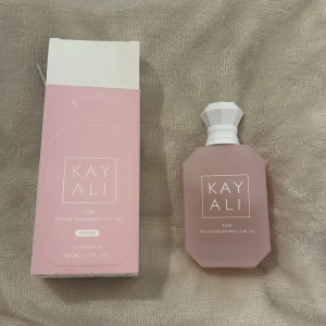 Kayali Yum Boujee Marshmallow 81 EdP - Söt och lyxig parfym från Kayali, Yum Boujee Marshmallow 81. Flaskan är matt rosa med vit diamantformad kork och rymmer 50 ml. Doftnoter av fresia, jordgubb, rosa marshmallow, krämig kokos, vispad vanilj och rosa mysk. Perfekt för dig som älskar gourmanddofter. Nästan ny, syns på bild 2 hur mycket jag har använt. Säljer för att den inte passar mig😊(förpackningen är lite sliten på sina ställen men inget som påverkar parfymen) 