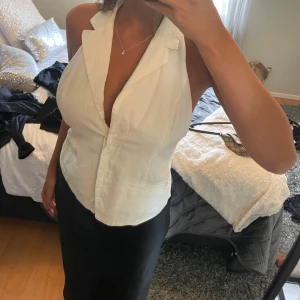 Vit ärmlös linnetopp med djup urringning - Säljer en vit topp med öppen rygg.