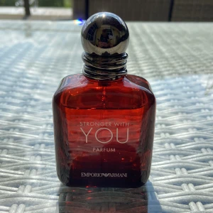 Emporio Armani Stronger With You Parfum - Emporio Armani Stronger With You Parfum i en stilren, fyrkantig flaska av mörkrött glas med silverfärgad rund metallkork. Flaskan har tydlig logga och text framtill. Parfymen har en modern och elegant design som sticker ut på hyllan. (30 ml)